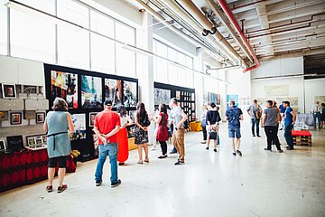 Menschen schauen Bilder in einer Ausstellungshalle an