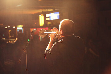 A man plays trumpet on the stage of the MensaBar