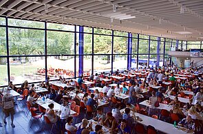Innenbereich mit Tischen, Stühlen und großer Glasfront