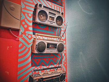 Old cassette recorders hang on a painted wall