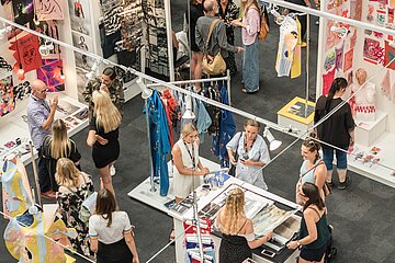 People in a flea market with fabric goods in an exhibition hall