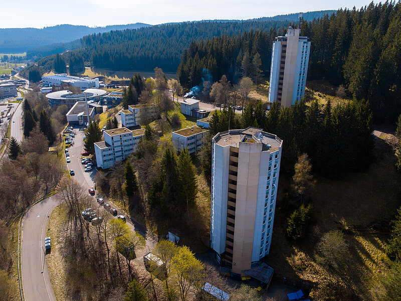 Wohnheim mit Hochhäusern am Waldrand, umgeben von Natur und Zufahrtsstraßen.