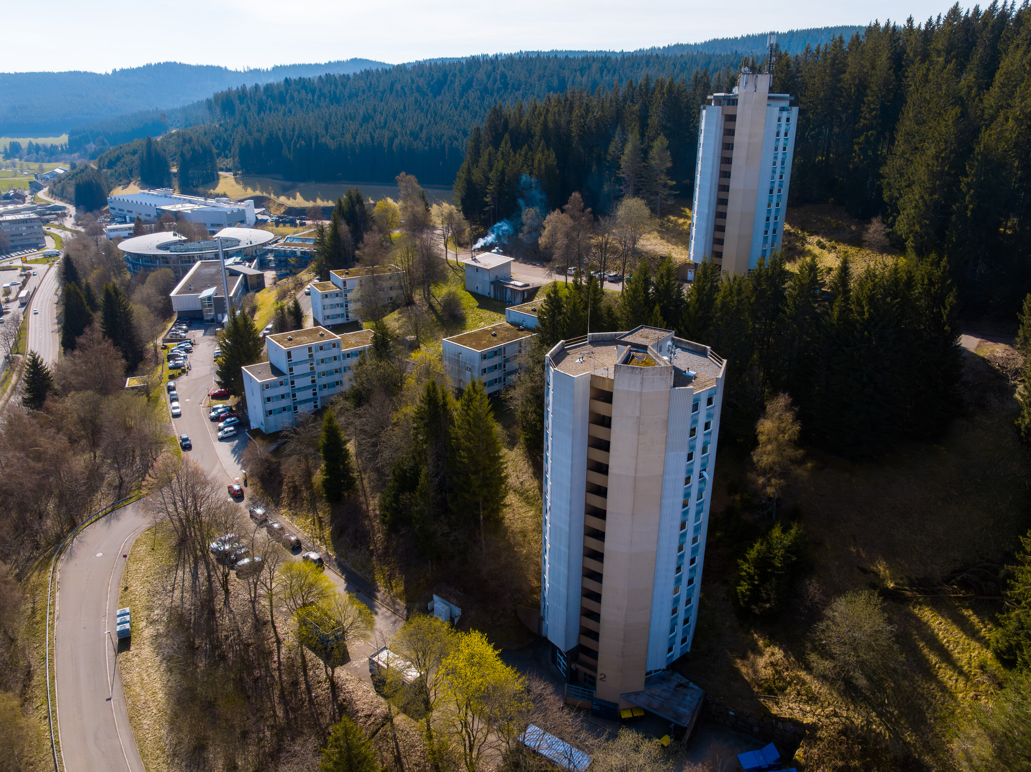 Wohnheim mit Hochhäusern am Waldrand, umgeben von Natur und Zufahrtsstraßen.